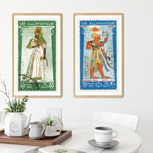 May include: Two framed vintage postage stamps featuring illustrations of Egyptian pharaohs in colorful traditional clothing. The stamps are from the United Arab Republic (UAR) and feature the text "الجمهورية العربية المتحدة" in Arabic.