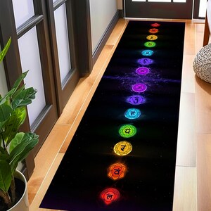 May include: A black and white runner rug with a rainbow design featuring seven chakras with Sanskrit symbols. The rug has a galaxy-like background.