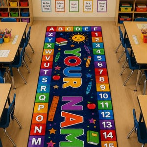 May include: A rectangular classroom rug featuring a dark blue center with the text YOUR NAME in large colorful letters, flanked by a column of letters A through Z and a column of numbers 1 through 20, decorated with icons like stars, books, and rainbows.
