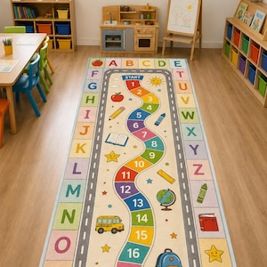 May include: A rectangular area rug featuring a winding path numbered from 1 to 20, surrounded by a border of the alphabet in colorful squares. The design includes illustrations of a school bus, backpack, globe, scissors, and pencils on a light background.