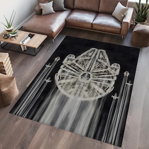 May include: A black and white area rug with a stylized image of the Millennium Falcon spaceship from Star Wars. The spaceship is surrounded by streaks of light, suggesting speed. The rug has a modern, abstract design.