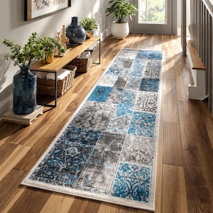 May include: A rectangular hallway rug with a patchwork design. The rug features a mix of blue, gray, and white patterned squares. The rug is placed on a wooden floor, and the overall aesthetic is modern and stylish.