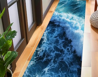 May include: A rectangular rug with a vibrant ocean wave design. The rug features shades of blue and white, depicting a dynamic wave pattern. The rug is placed on a wooden floor, adding a touch of coastal decor to the space.