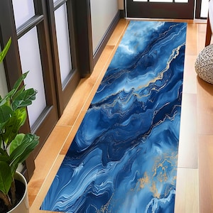 May include: A blue and gold abstract runner rug with a marbleized design. The rug is long and rectangular, ideal for adding a touch of modern style to any room.