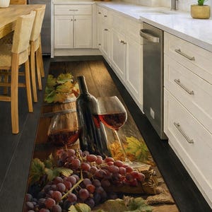 May include: A rectangular kitchen rug featuring a wine theme. The rug displays a wine bottle, two glasses of red wine, a wooden barrel, and a bunch of grapes. The color palette includes shades of brown, red, and green.