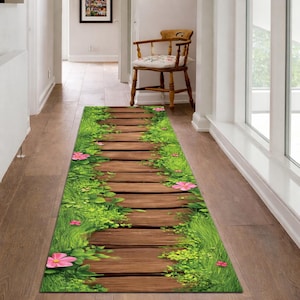 May include: A rectangular hallway rug featuring a wooden pathway design with green grass and pink flowers on both sides. The rug is designed to look like a path through a garden.