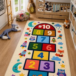 May include: A rectangular beige hopscotch rug with colorful squares numbered 1 through 10. The rug features whimsical designs of rockets, stars, clouds, a moon, an owl, and a fox. The rug is designed for children's play.