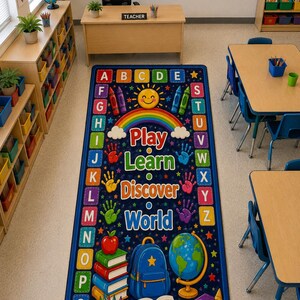 May include: A rectangular classroom rug with a dark blue background featuring the alphabet in colorful squares along the borders, a central rainbow, and the text Play Learn Discover World, surrounded by illustrations of books, a globe, and a backpack.
