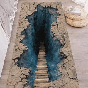 May include: A rectangular rug with a 3D optical illusion design. The rug depicts a deep blue chasm with a wooden staircase leading into darkness, surrounded by cracked, tan earth.