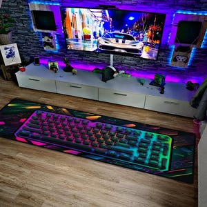 Könnte beinhalten: Gaming-Setup mit einer mechanischen Tastatur mit RGB-Beleuchtung auf einem großen Mauspad. Die Tastatur hat schwarze Tastenkappen und einen farbenfrohen Schein. Das Mauspad hat ein lebendiges, abstraktes Design. Das Setup befindet sich auf einem Holzboden.