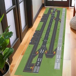 May include: A green and gray rug with a detailed design of an airport runway. The runway has markings for taxiing, takeoffs, and landings. The rug is perfect for a playroom or a child's bedroom.