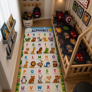 May include: A rectangular children's area rug featuring a colorful alphabet grid with illustrations of animals from A to Z. The rug includes the text ALPHABET at the top and LEARN, PLAY, GROW at the bottom, set against a blue and green background.