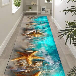 Peut inclure: Un long tapis rectangulaire avec un motif de scène de plage. Le tapis présente une plage de sable avec des étoiles de mer et des coquillages, se transformant en un océan turquoise vibrant. Conçu pour un couloir.