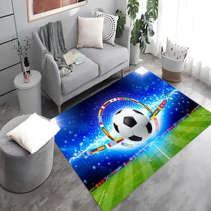 Pode incluir: Um tapete azul e verde com uma bola de futebol no centro, cercada por bandeiras de diferentes países. A bola de futebol é branca com painéis pretos. O tapete tem um fundo azul com estrelas brancas e um campo verde no canto inferior direito.