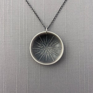 May include: A silver necklace with a round pendant featuring the words "joy", "peace", "love", "wonder", "hope", "faith", "gratitude", "compassion", "kindness", "strength", "wisdom", "courage", "inspiration", "joy", "peace", "love", "wonder", "hope", "faith", "gratitude", "compassion", "kindness", "strength", "wisdom", "courage", "inspiration" inscribed on it.