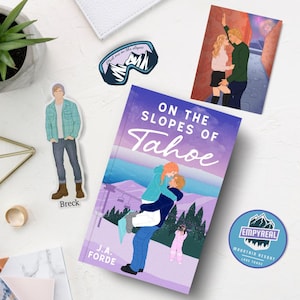 May include: A purple and pink book cover with the title "On the Slopes of Tahoe" in white cursive font. The cover features a couple skiing down a mountain with a blue sky and white clouds in the background. There is a sticker on the book that says "Meet me on the slopes".