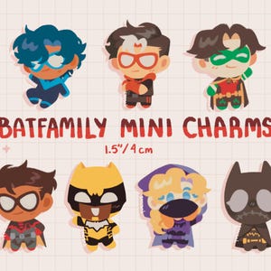 Puede incluir: Un conjunto de siete dijes ilustrados de personajes con el texto BATFAMILY MINI CHARMS 1.5"/4 cm. Los personajes presentan diseños estilizados en varios colores incluyendo azul, rojo, verde, amarillo, morado y negro, midiendo 4 cm de altura.