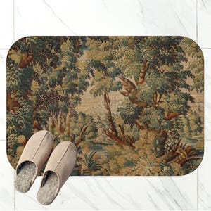 May include: A rectangular bath mat with rounded corners featuring a detailed forest landscape print in shades of green, brown, and beige. A pair of light beige slip-on slippers with grey interior lining are placed on the lower left corner.