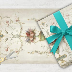 May include: A gift wrapped in floral patterned paper with a teal ribbon and bow. A sheet of matching paper and gold scissors are next to the gift. The floral design includes vases and bouquets.