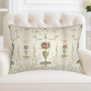 May include: Rectangular decorative pillow with a vintage floral design. The pillow features a cream-colored background with repeating patterns of vases filled with flowers, and delicate floral vines in shades of pink, green, and gold.