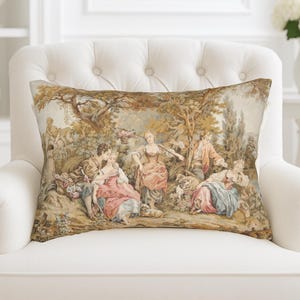 Può includere: Cuscino decorativo rettangolare con una scena pastorale. Il cuscino presenta un design arazzo con figure in abiti d'epoca, alberi e un paesaggio nei toni del beige, marrone, rosa e blu. Su una poltrona bianca.