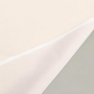 May include: A folded piece of cream-colored fabric featuring a smooth, matte texture. The fabric is layered, revealing a clean, straight white stitched hem along the diagonal fold that separates the two sections of the material.