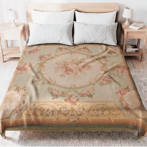 May include: A floral patterned bedspread with a light green background and a central oval design featuring pink roses and other flowers. The bedspread has a decorative border and is placed on a bed with white pillows.