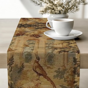 Puede incluir: Un camino de mesa rectangular con un diseño de tapiz tejido que muestra un faisán, follaje y columnas arquitectónicas en tonos marrón, bronceado y verde apagado. La tela tiene una apariencia texturizada con un patrón detallado.