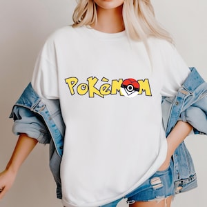Puede incluir: Camiseta blanca con la palabra "Pok&eacute;mon" en letras amarillas con contorno negro. La "o" del medio se reemplaza con un gr&aacute;fico de Pok&eacute; Ball rojo y blanco. La camiseta se usa con una chaqueta y pantalones cortos de mezclilla.