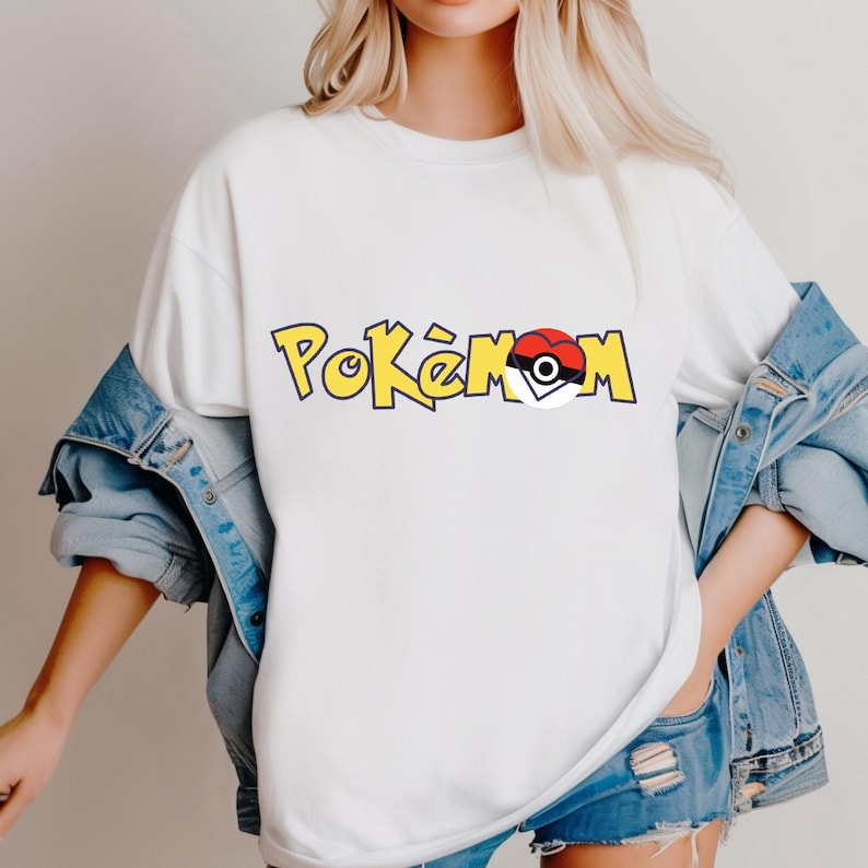 Puede incluir: Camiseta blanca con la palabra "Pok&eacute;mon" en letras amarillas con contorno negro. La "o" del medio se reemplaza con un gr&aacute;fico de Pok&eacute; Ball rojo y blanco. La camiseta se usa con una chaqueta y pantalones cortos de mezclilla.