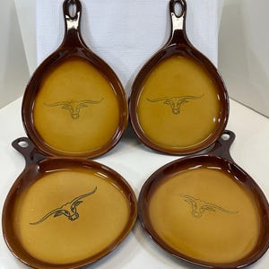 May include: Set of four brown ceramic serving dishes with a brown handle. Each dish features a black silhouette of a longhorn steer with large horns.