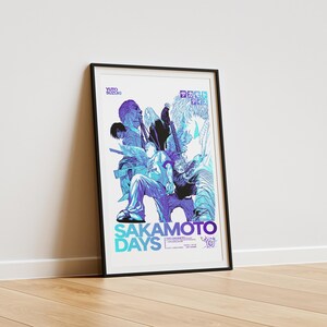 Framed poster leaning against white wall, atop wooden floor, lit by natural light. The framed poster contains composited manga panels from "Sakamoto Days," colored in an blue and purple gradient.