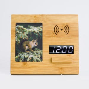 May include: A wooden picture frame with a digital clock and a wireless charging pad. The frame has a photo of a squirrel in a tree. The clock displays the time 12:00.