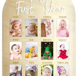 May include: A wooden monthly milestone photo board with a light brown finish. The board is arched at the top and features the words 'My First Year' in white script. It has twelve rectangular photo frames, each labeled with a month from one to twelve. The board is designed to display baby photos.