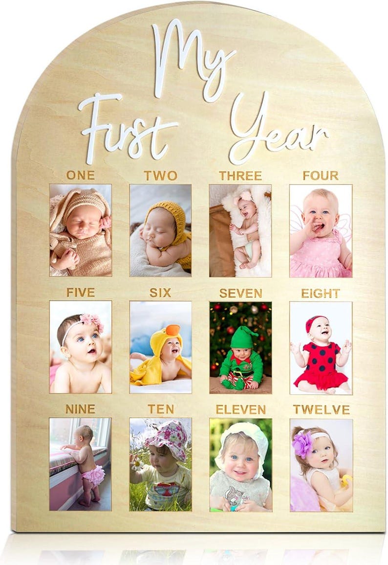 May include: A wooden monthly milestone photo board with a light brown finish. The board is arched at the top and features the words 'My First Year' in white script. It has twelve rectangular photo frames, each labeled with a month from one to twelve. The board is designed to display baby photos.