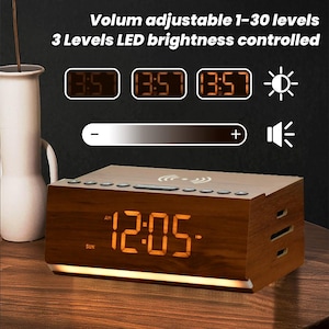 May include: A wooden alarm clock with a digital display showing 12:05 AM. The clock has a built-in wireless charging pad and volume controls. The clock also has a brightness control with three levels. The clock is on a wooden surface.