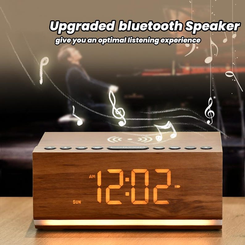May include: A wooden alarm clock with a digital display showing 12:02 AM. The clock has a built-in Bluetooth speaker and a wireless charging pad. The clock is on a wooden surface with a blurred background.