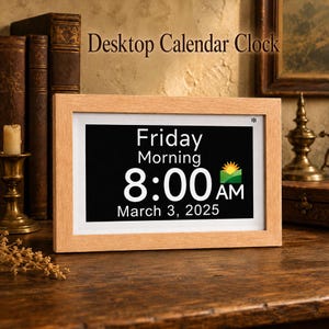 May include: A rectangular desktop calendar clock with a light wood frame. The digital display shows the text Friday, Morning, 8:00 AM, and March 3, 2025, alongside a small sun and hill icon. The device features a white inner border.