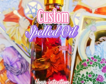 Può includere: Una bottiglia di vetro piena di fiori secchi e olio. La bottiglia ha un tappo dorato e un contagocce. L'etichetta sulla bottiglia recita "Custom Spelled Oil" e "Astral Heart". Il testo "Your intention Your magic" è anche sull'etichetta.