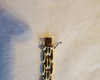 May include: A gold chain bracelet with a clasp closure. The chain is made of interlocking oval links.