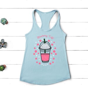 May include: Light blue tank top with a graphic of a strawberry latte. The graphic includes a pink and white cup with whipped cream and a straw. The text "Strawberry Latte" is above the cup.