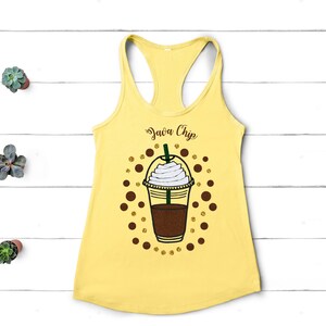 May include: Yellow tank top with a brown and white coffee cup graphic and the text "Java Chip" in brown text. The coffee cup has a brown lid and a white swirl of whipped cream on top.