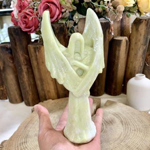 Peut inclure: Une sculpture d'ange en jade vert aux ailes déployées. L'ange est sculpté dans un style minimaliste avec une finition lisse et polie.