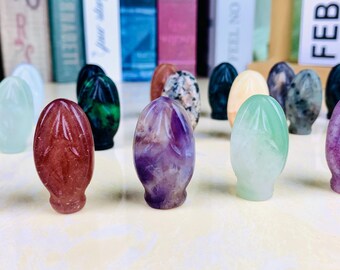 May include: A collection of polished oval-shaped stones in various colors, including green, purple, pink, and white. The stones are smooth and have a glossy finish.