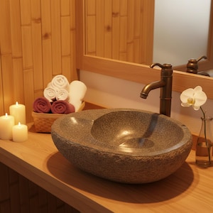 May include: A stone vessel sink with a bronze faucet, set on a wooden countertop. Rolled white and burgundy towels sit in a wicker basket. Lit candles and a small vase with an orchid complete the spa-like bathroom scene.