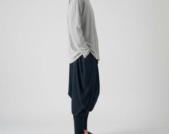 May include: A light gray long-sleeve shirt paired with dark navy drop-crotch pants and navy slip-on shoes. The outfit is simple and casual, suitable for everyday wear. The pants have a unique, relaxed fit.