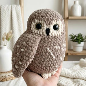 以下が含まれることがあります： 茶色とクリーム色の手編みのかぎ針編みフクロウ。 ぬいぐるみフクロウは、大きな黒い目、黒いくちばし、白い斑点模様が特徴です。 柔らかく、抱きしめたくなるおもちゃです。