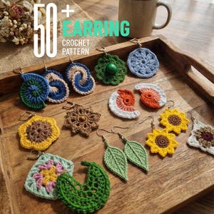 Könnte beinhalten: Eine Sammlung handgefertigter Häkelohrringe in verschiedenen Designs, darunter Blumen, Blätter und abstrakte Formen. Die Ohrringe werden auf einem Holztablett präsentiert, mit dem Text "50+ EARRING CROCHET PATTERN" in der oberen linken Ecke.