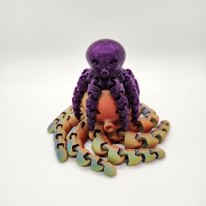 Könnte beinhalten: Eine 3D-gedruckte Oktopus-Figur mit einem violetten Kopf und regenbogenfarbenen orangen Tentakeln.