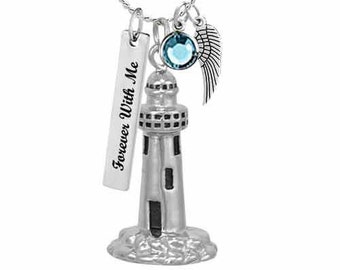May include: Silver-toned lighthouse pendant necklace with a blue gemstone, a small wing charm, and a rectangular tag that reads "Forever With Me". The lighthouse has black windows and sits on a textured base.